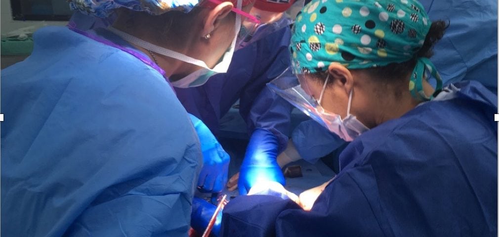 A group of surgeons performing surgery in an operating room photographed.