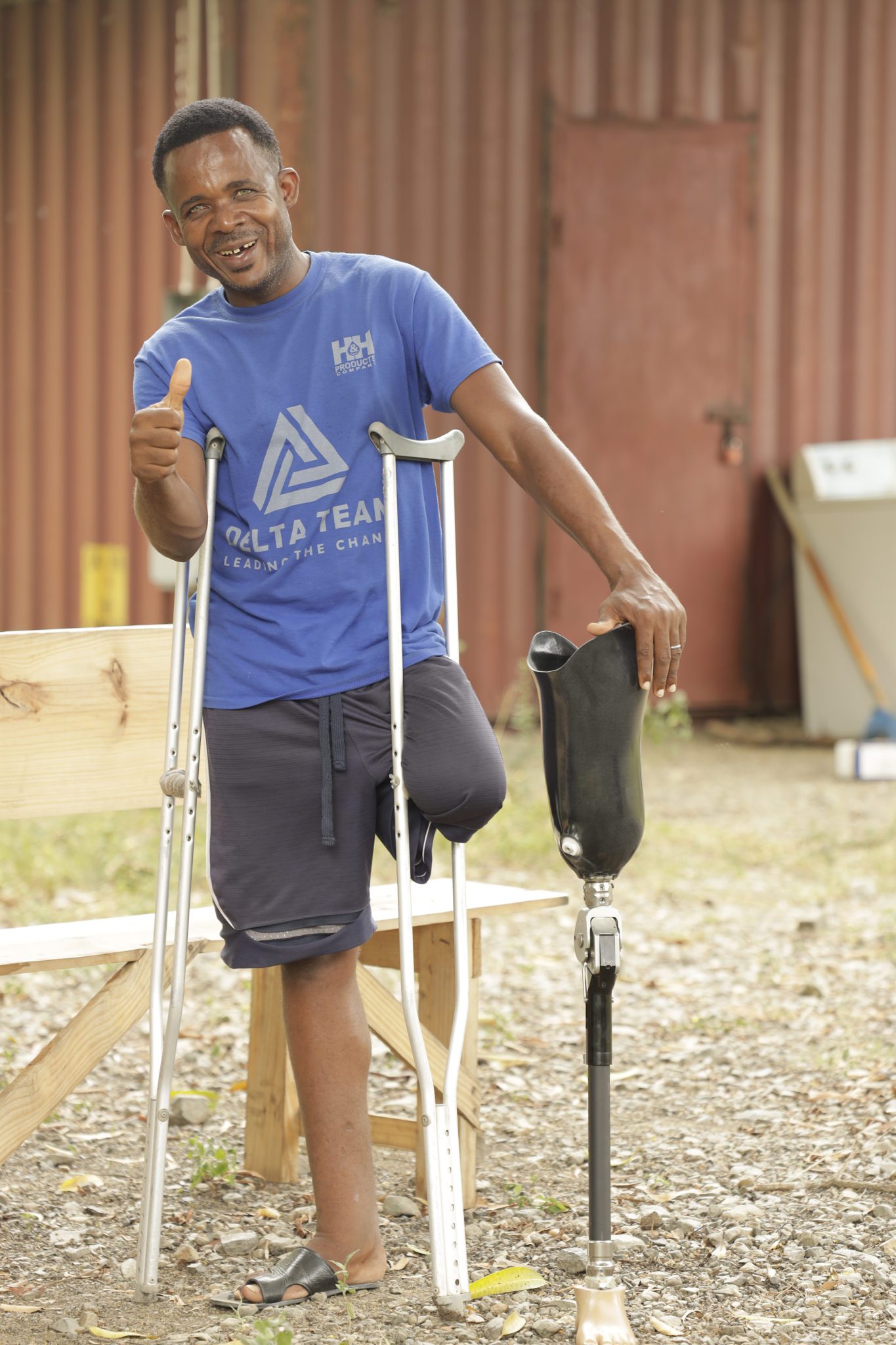 A man in a blue shirt with a pair of crutches receiving medical care.