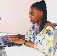 A focused woman with braided hair using a laptop at a desk.
